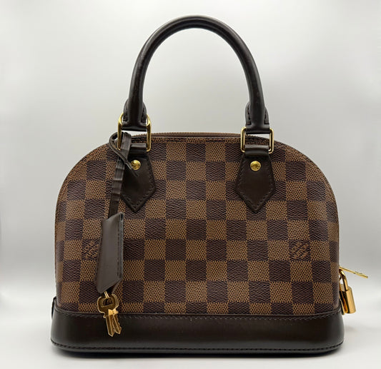 Louis Vuitton Alma BB in Damier Ebène coated canvas, front view showing structured silhouette and gold-tone LV padlock