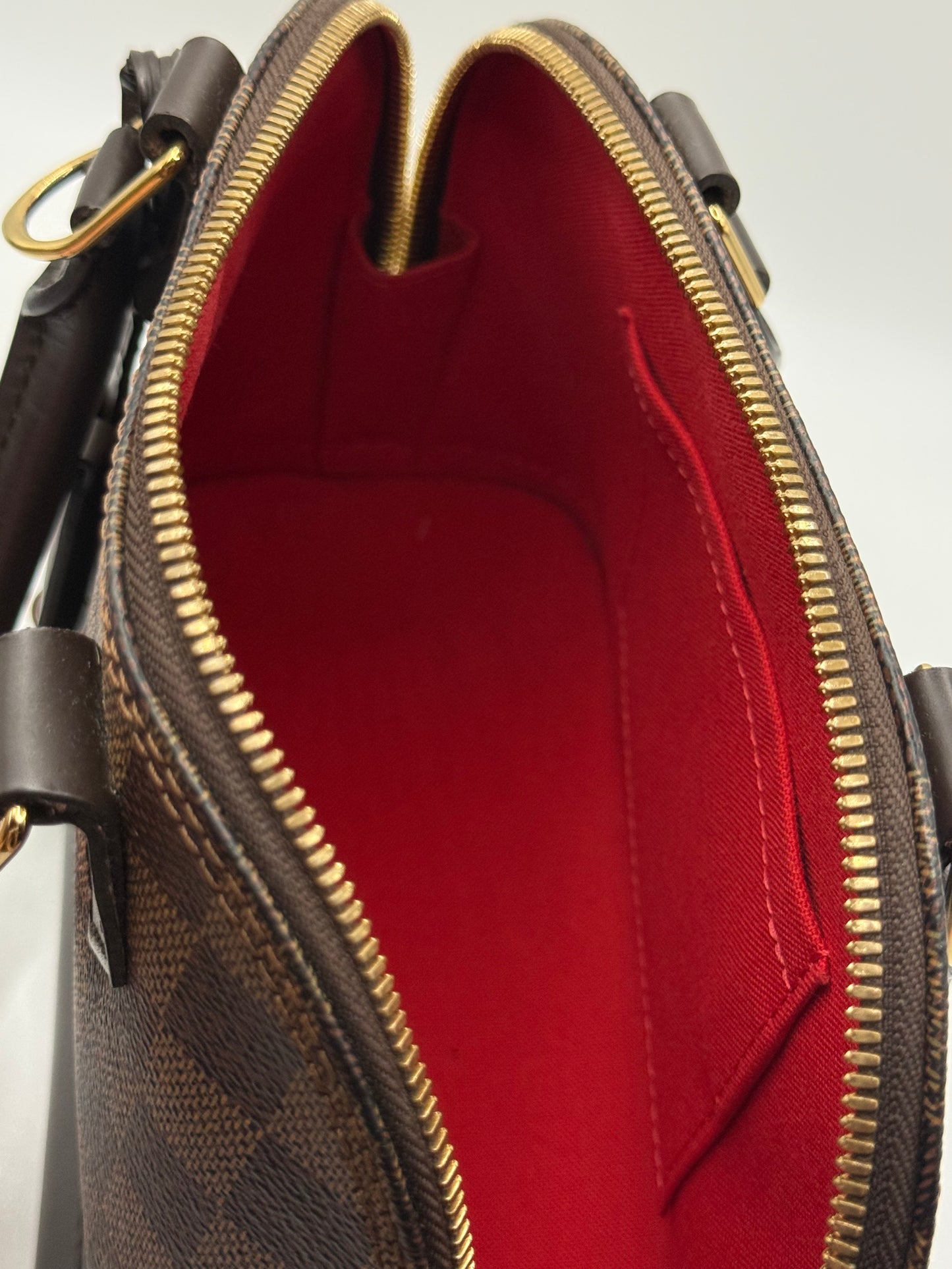 Louis Vuitton Alma BB Damier Ebène, detail shot of top zip closure and rolled leather handle attachment