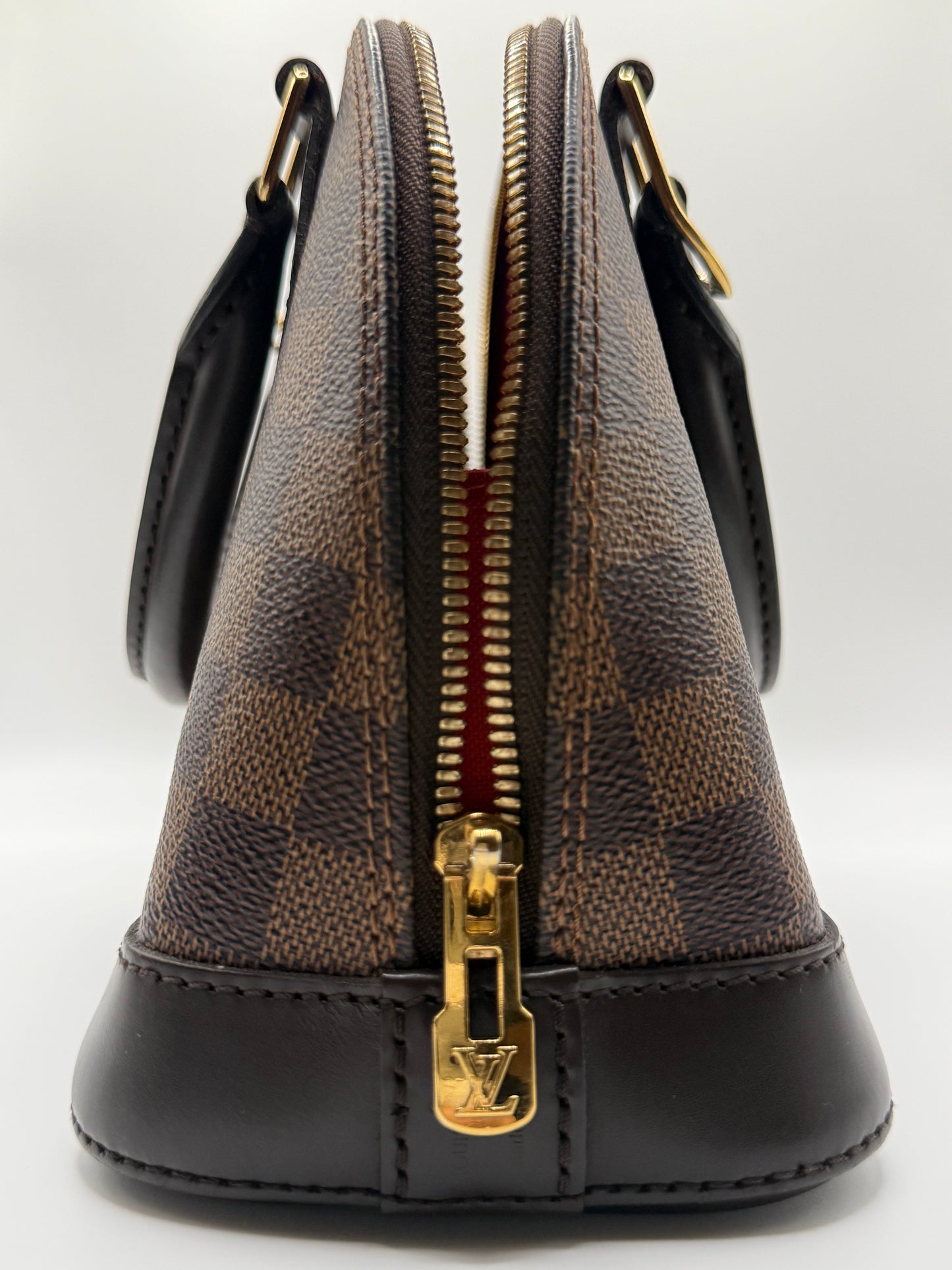 Louis Vuitton Alma BB Damier Ebène, side profile showing structured barrel shape and dark brown leather trim