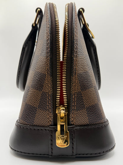 Louis Vuitton Alma BB Damier Ebène, side profile showing structured barrel shape and dark brown leather trim