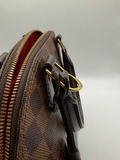 Louis Vuitton Alma BB Damier Ebène, close-up of gold-tone LV padlock and key with leather tab
