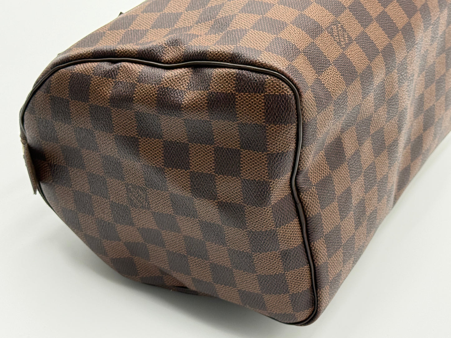 Corner and base detail of the Louis Vuitton Speedy 30, showing leather trim and stitching