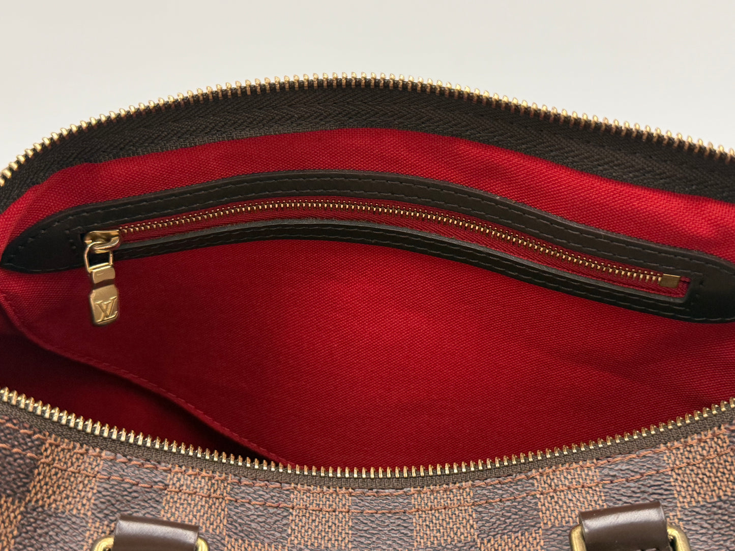 Interior zip pocket of the Louis Vuitton Speedy 30 in red textile lining